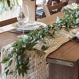 Gedekte tafel met macrame tafelloper en groene streng met blaadjes